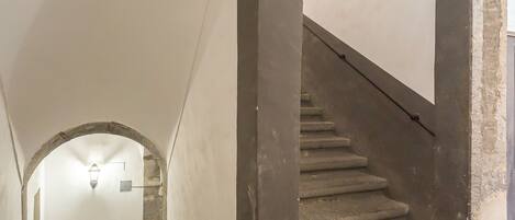 A staircase with a tiled landing and a fire extinguisher on the wall.