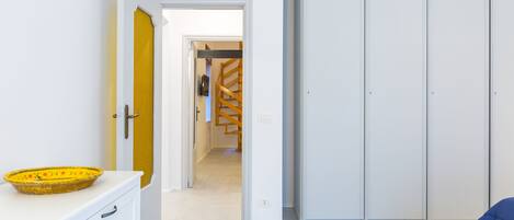 A hallway with a white wardrobe, a yellow door, and a white wall.