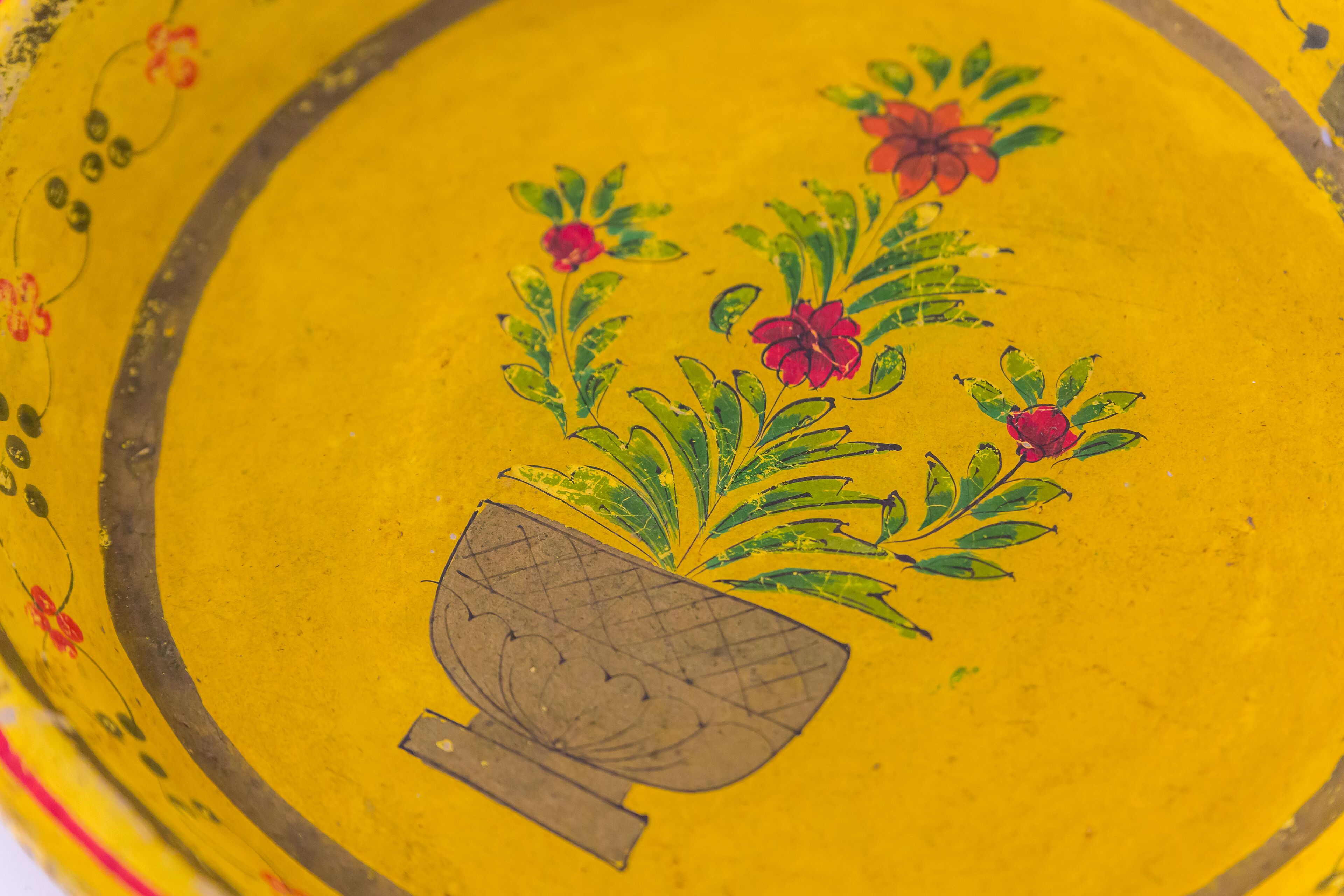 A yellow surface with a painted design of a plant and a pot.