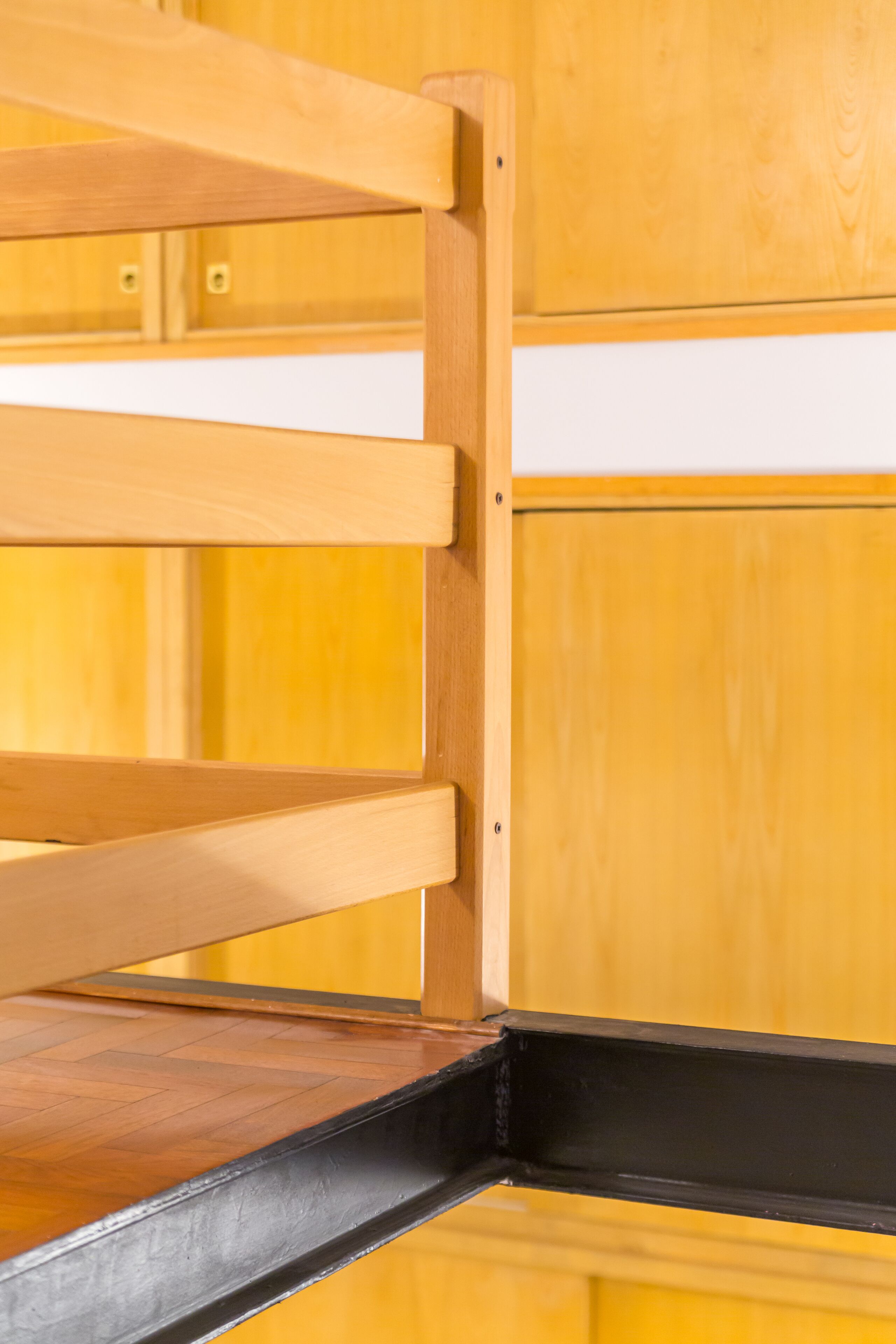 Ein Holzbett mit Etagen und einem schwarzen Metallgestell.