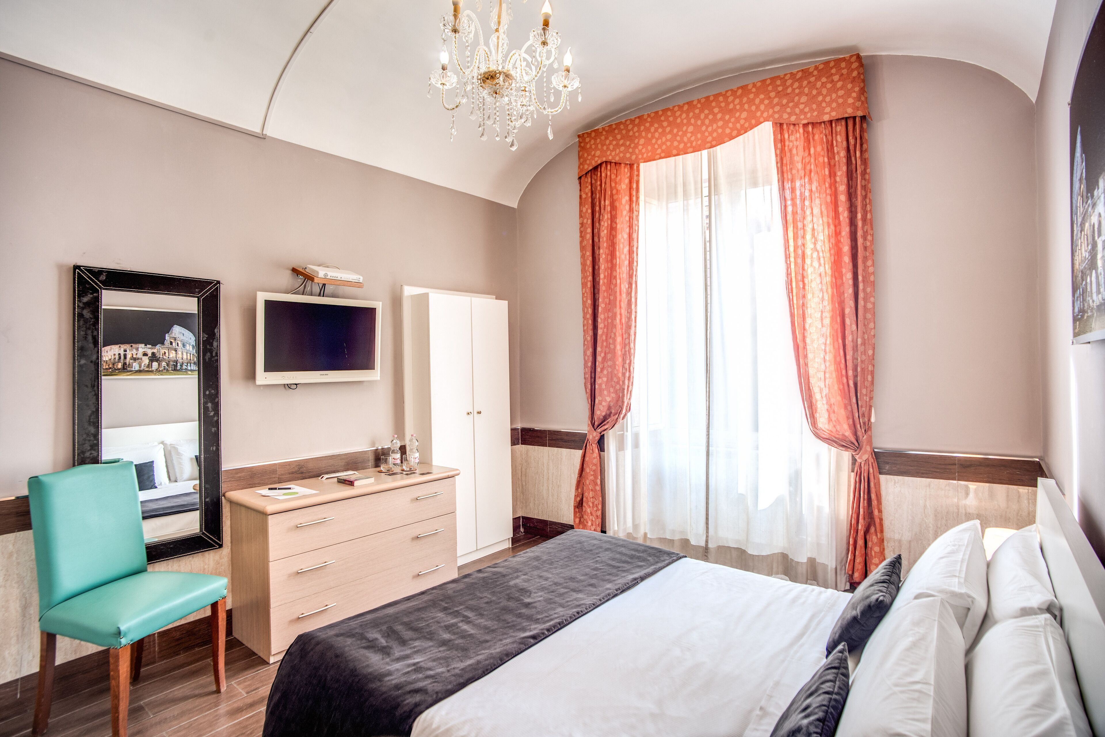 Una camera d'albergo con un letto, una televisione, una scrivania e una sedia.