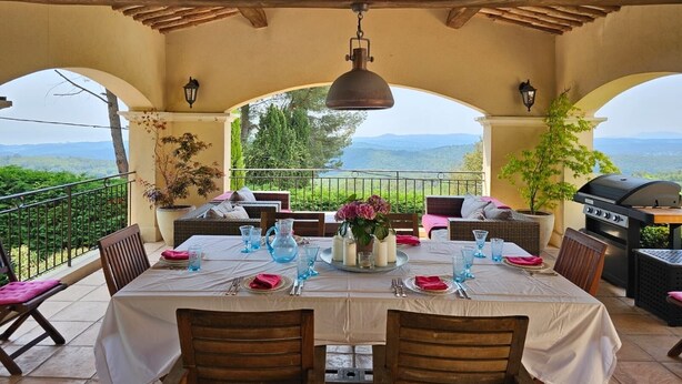 A covered outdoor dining area with a table set for four, surrounded by chairs, a grill, and potted plants. - Beautiful Villa with panoramic seaviews,  easy walking distance to the village (Tourrettes-sur-Loup)
