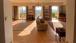 A spacious living room with a sofa, a TV, and a view of the outdoors. - Beautiful Villa with panoramic seaviews,  easy walking distance to the village (Tourrettes-sur-Loup)