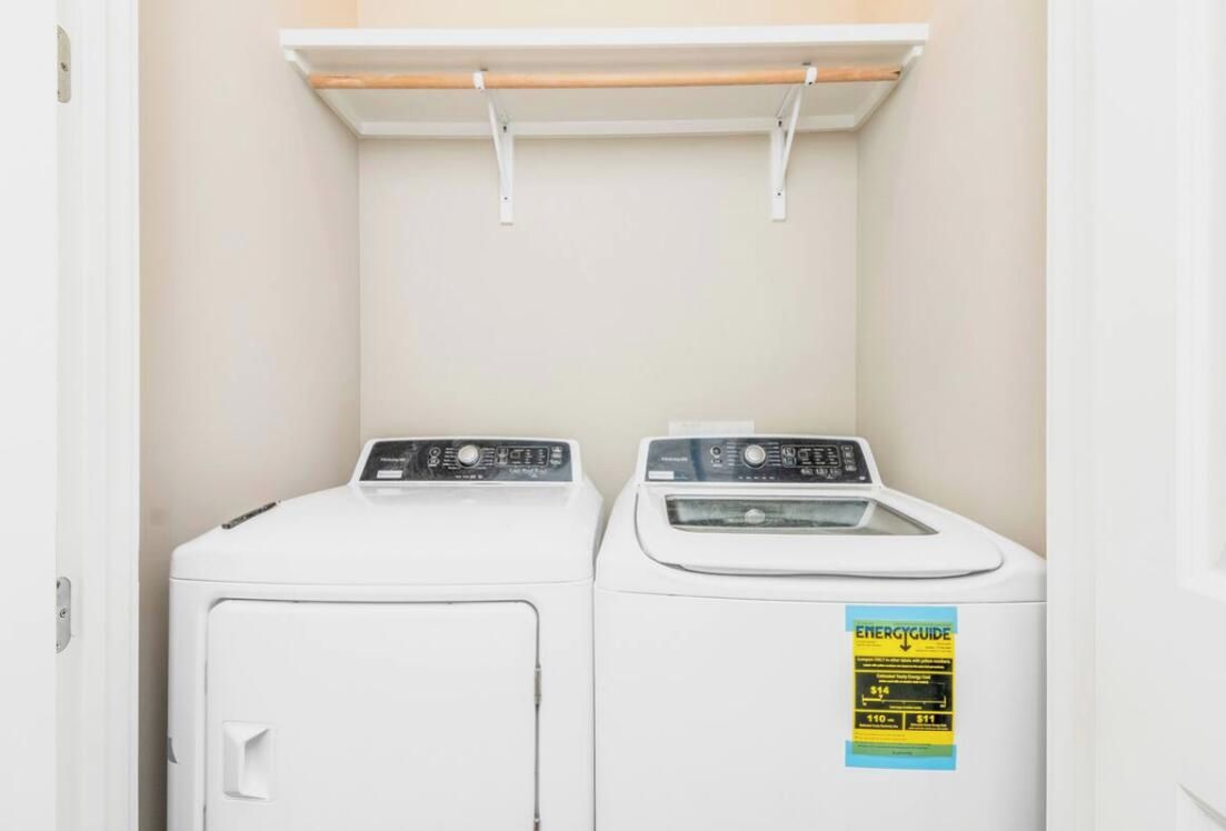 A laundry area with two white washing machines and a shelf above them.