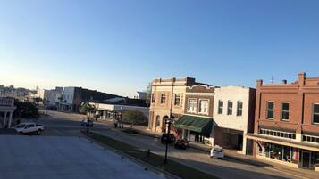 A street view with buildings, a clear sky, and parked cars.