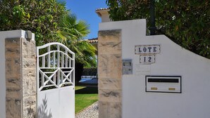 A gated entrance with a stone wall, a metal gate, and a sign that reads "LOTE 12".