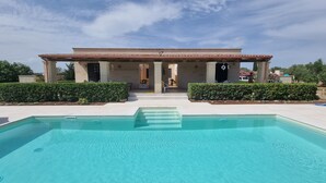 A modern house with a swimming pool in front.
