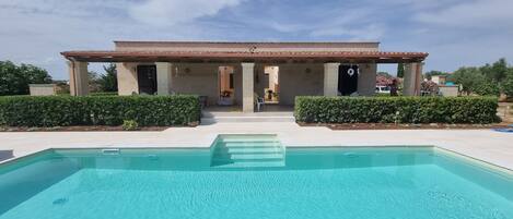A modern house with a swimming pool in front.