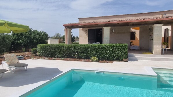 A swimming pool with a covered patio area, a chair, and a green umbrella. - VILLA AMICORUM House WEST, 10 x 4 m pool (San Pietro In Bevagna)