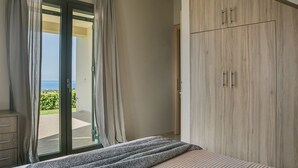 Une chambre à coucher comprenant un lit, une armoire et une porte-fenêtre coulissante donnant sur un balcon avec vue.