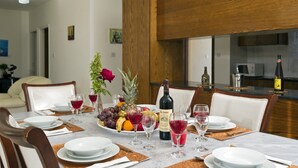 A dining area with a table set for four, featuring a bottle of wine, fruit, and glasses. - Luxury villa on mountainside with sea views (Kathikas)