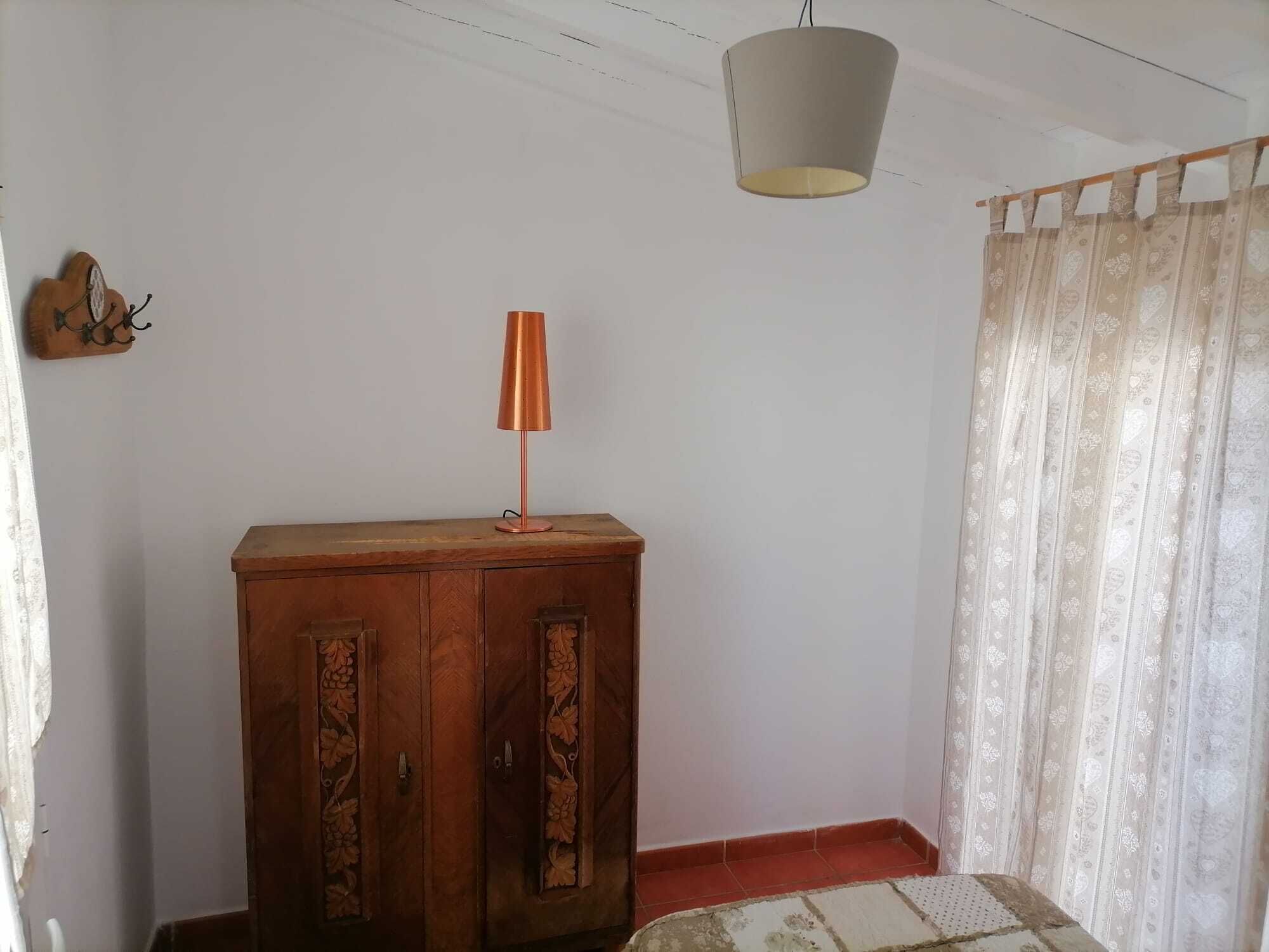 A room with a wooden cabinet, a hanging lamp, and a patterned curtain.