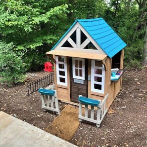 Cozy playhouse with a front door, windows, and a small porch.