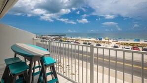 Varanda com vista para a praia e carros estacionados.