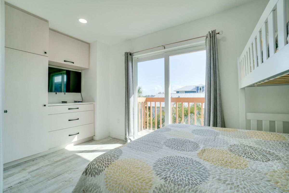 Een slaapkamer met een bed, een televisie, een balkon en uitzicht.