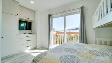 Een slaapkamer met een bed, een televisie, een balkon en uitzicht.