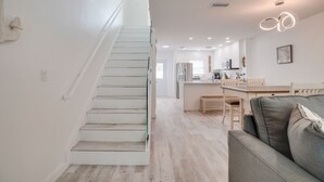 Um interior moderno com escada, área de refeições e cozinha.