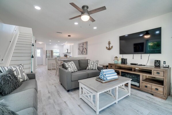 A modern living room with a sofa, coffee table, TV, and entertainment unit. - Sunset Landings 5 (Bradenton Beach)