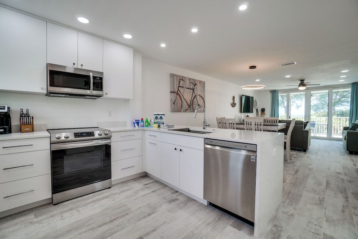 Una cocina moderna con armarios blancos, electrodomésticos de acero inoxidable y una isla central.