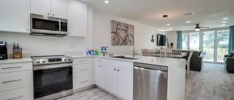 Una cocina moderna con armarios blancos, electrodomésticos de acero inoxidable y una isla central.