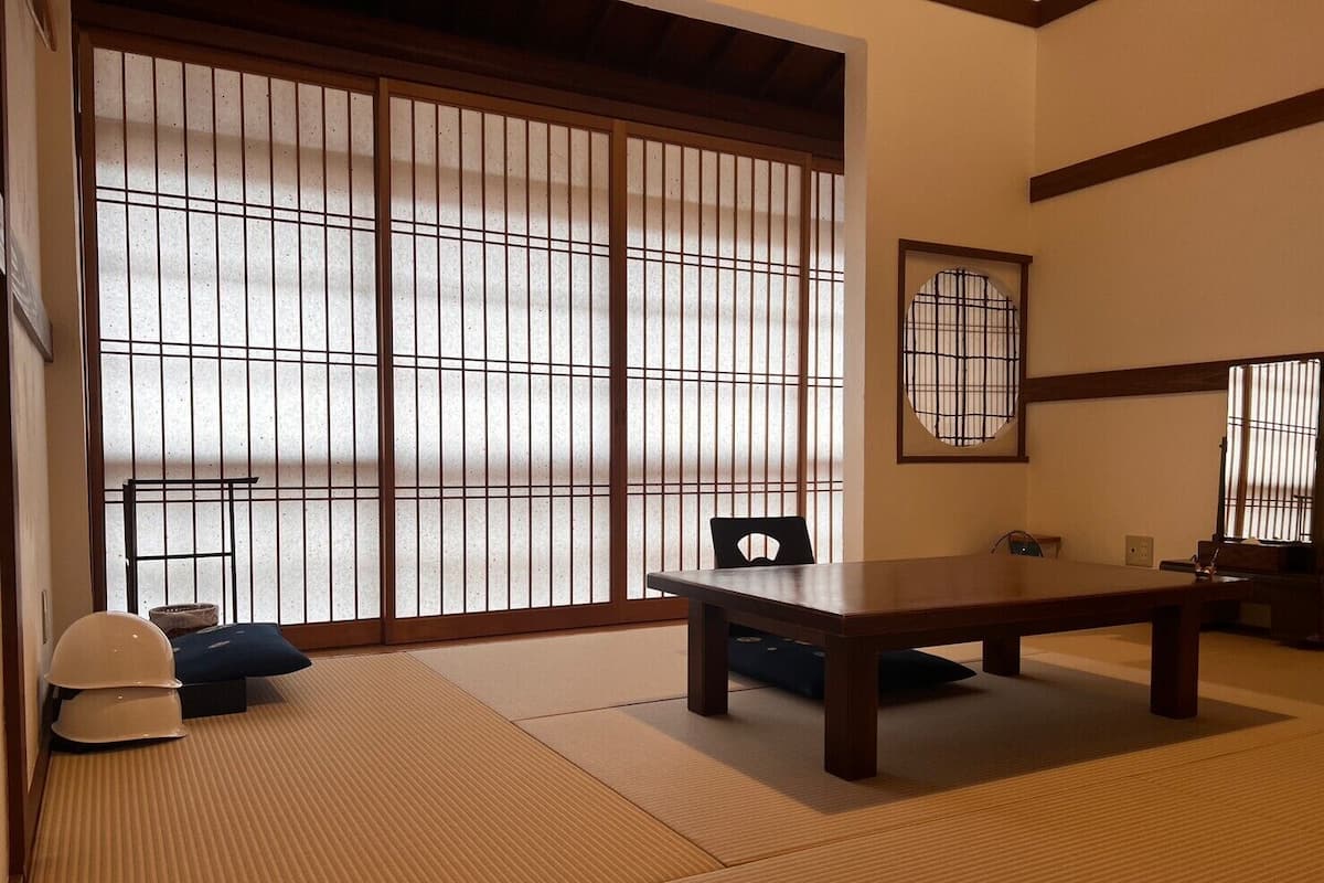 A traditional Japanese room with tatami flooring, a low table, and sliding doors.