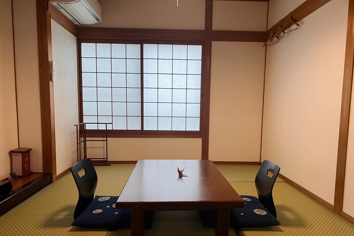 Une pièce de style japonais traditionnel, avec un sol recouvert de tatamis, une table basse et des paravents en papier de riz (shoji).