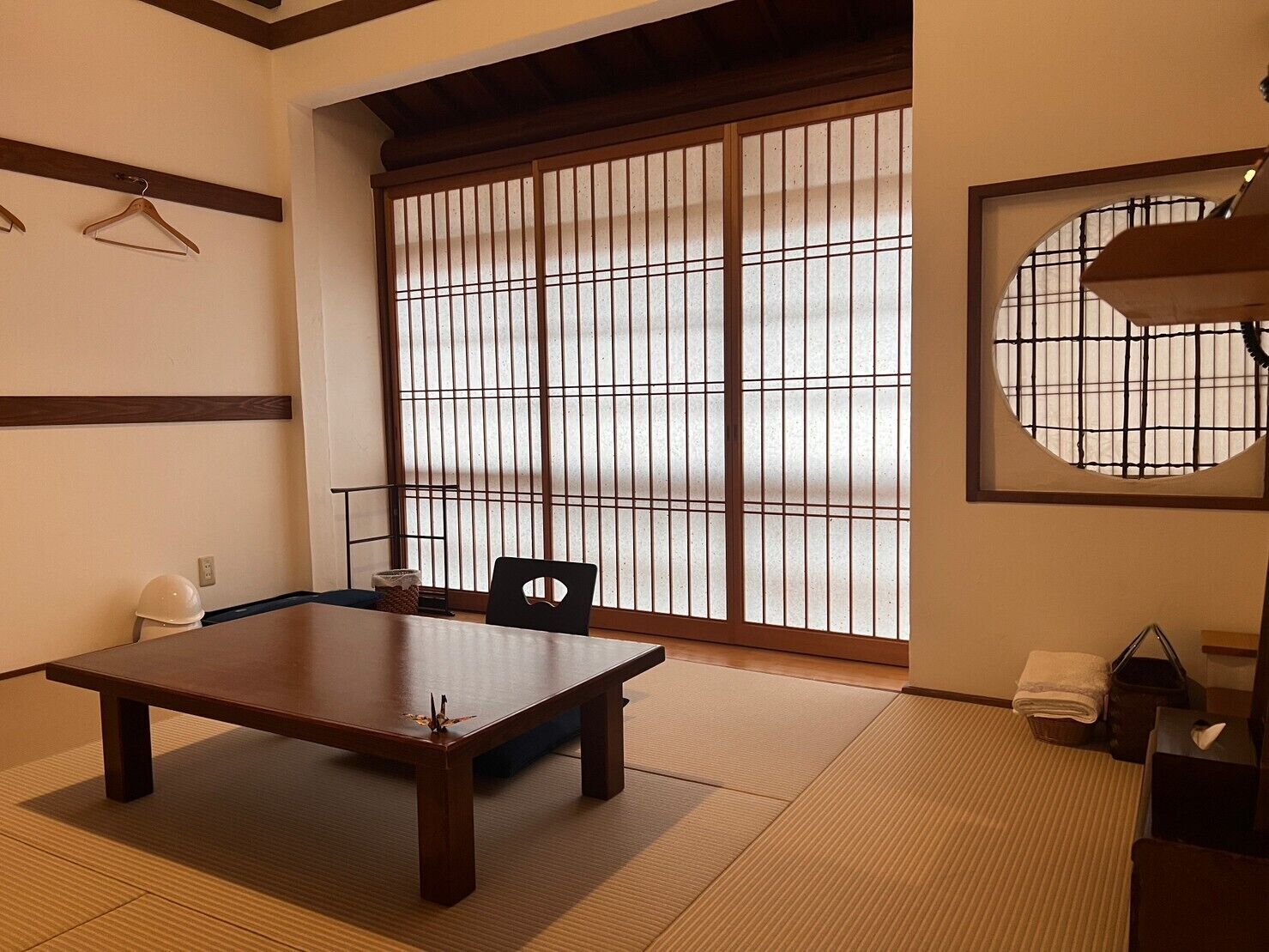 A traditional Japanese room with tatami flooring, a low table, a chair, and a sliding shoji screen.