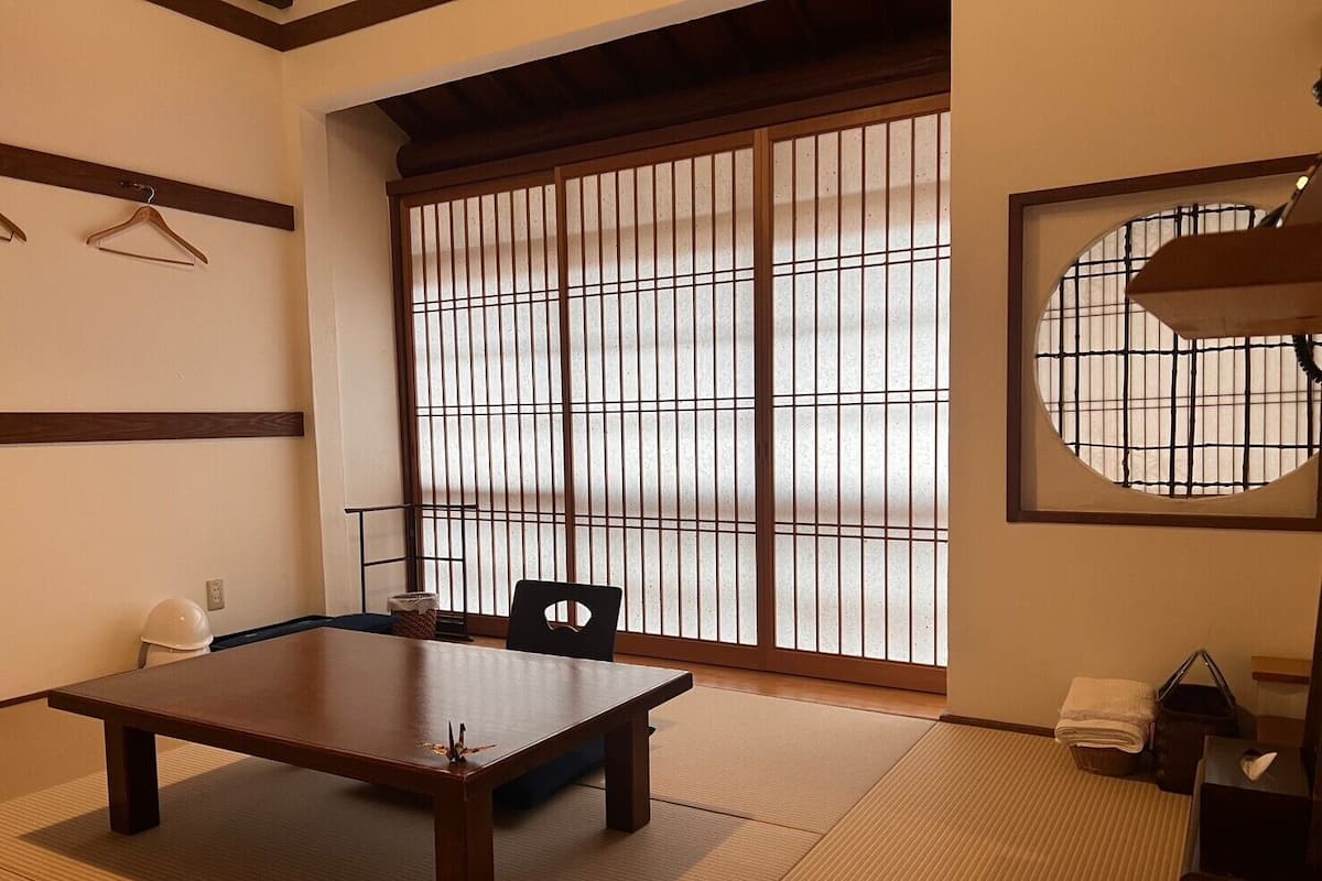 A traditional Japanese room with tatami flooring, a low table, a chair, and a sliding shoji screen.