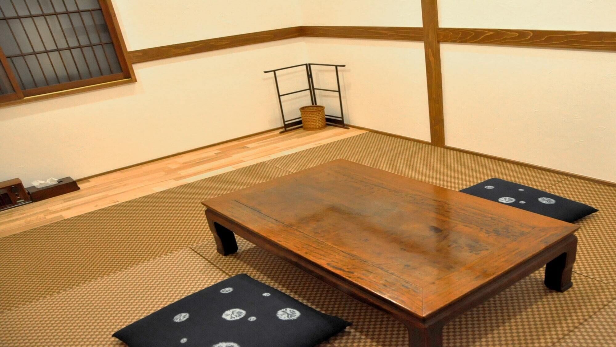 Una habitación con esteras de tatami, una mesa de madera y cojines.