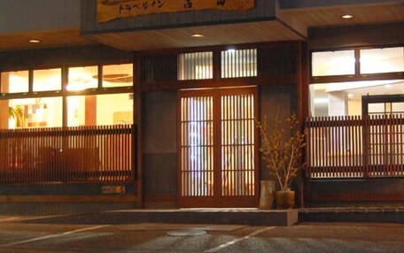 A traditional Japanese building with a wooden entrance, a sign above the door, and a view of the interior through the windows.