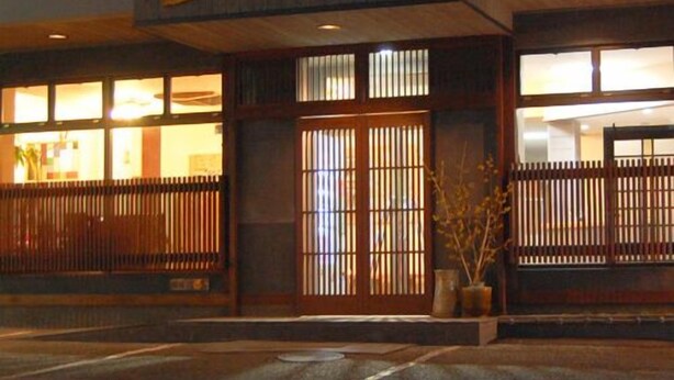 A traditional Japanese building with a wooden entrance, a sign above the door, and a view of the interior through the windows. - Travel Inn Yoshitomi (Taketa)