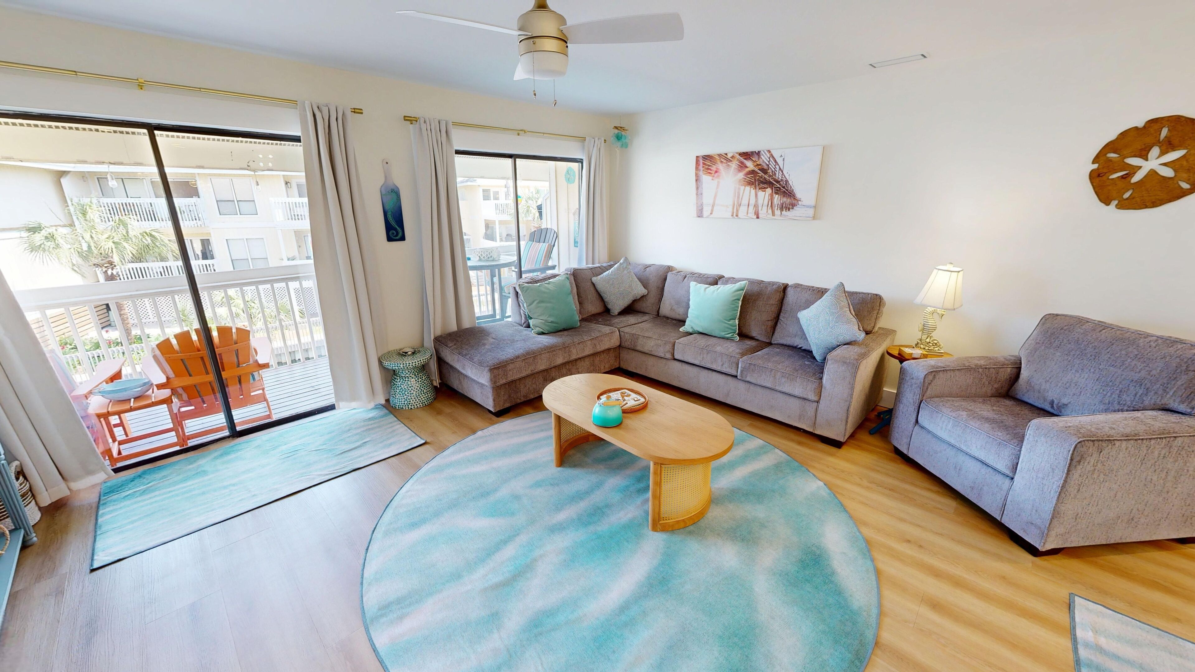 A modern living room with a grey sofa, a round coffee table, and a view of the balcony.