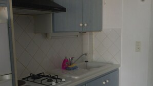 Une cuisine équipée d’une cuisinière à gaz, d’un évier et de meubles de rangement bleus.