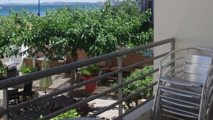 Un balcon avec vue sur la mer, des plantes en pot et des chaises en métal.
