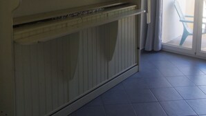 Une pièce dotée d’une grande armoire, d’une porte-fenêtre coulissante donnant sur un espace extérieur et d’un sol carrelé.