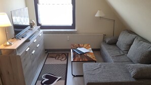 A modern living room with a sofa, a coffee table, a TV, and a lamp.