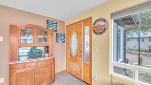 Un couloir avec une armoire en bois, une porte vitrée et une fenêtre donnant sur l’extérieur.