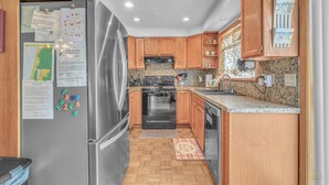 Une cuisine avec des meubles en bois, un réfrigérateur en acier inoxydable, une cuisinière et un évier.