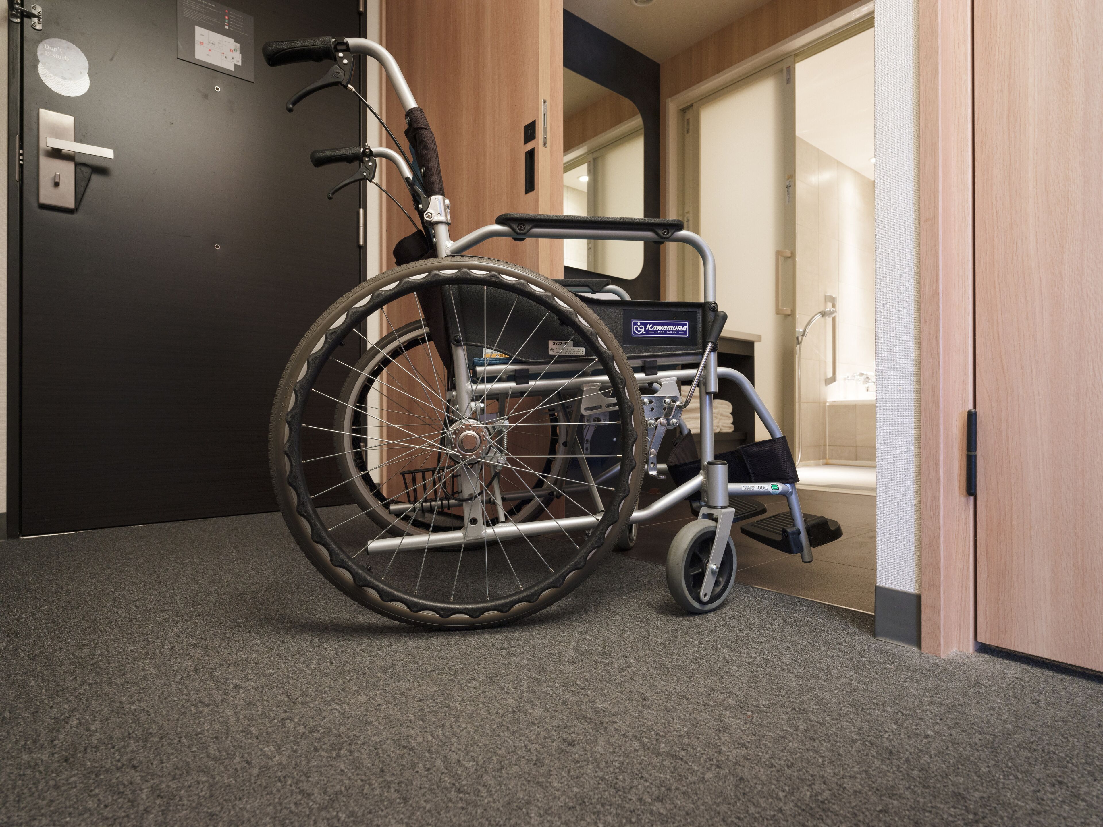 A wheelchair in a room with a wooden door and a tiled floor.