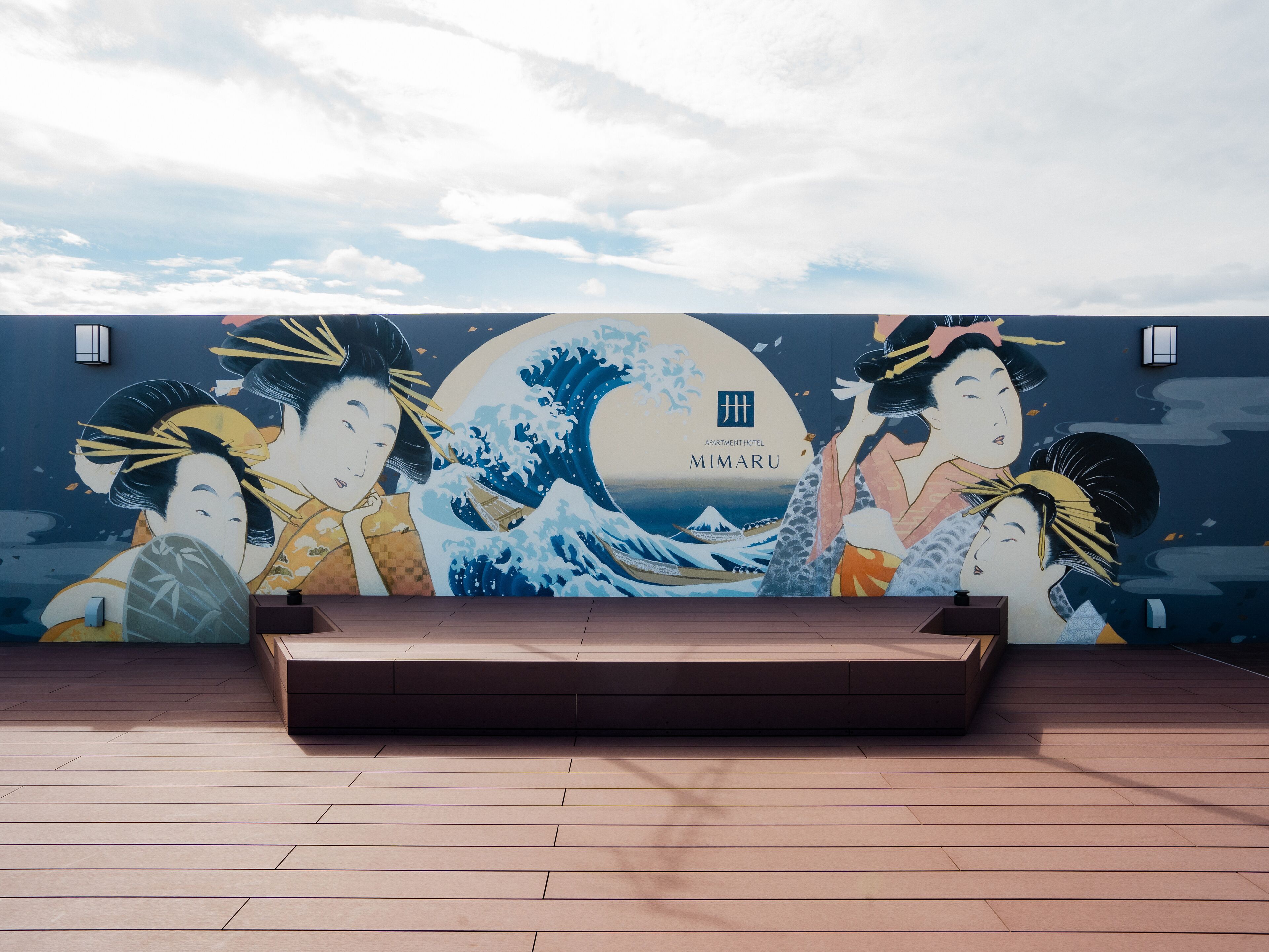 A mural of Japanese art on a hotel wall, including a wave and figures in traditional attire.