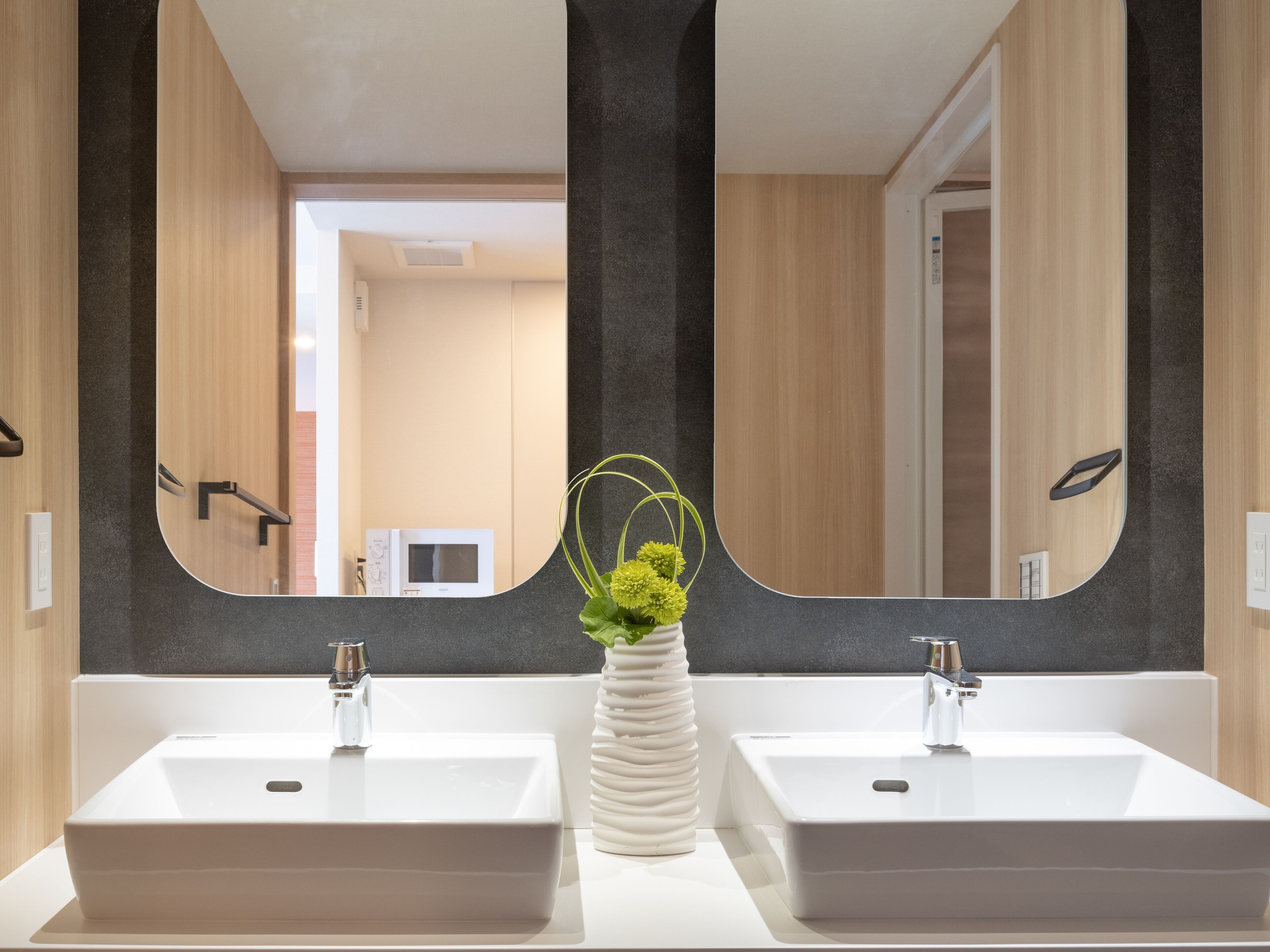 Une salle de bain moderne avec deux lavabos, un miroir et une plante en pot.