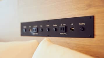 A power strip with multiple outlets and USB ports, including AC-100V and USB charging options, mounted on a wooden surface.