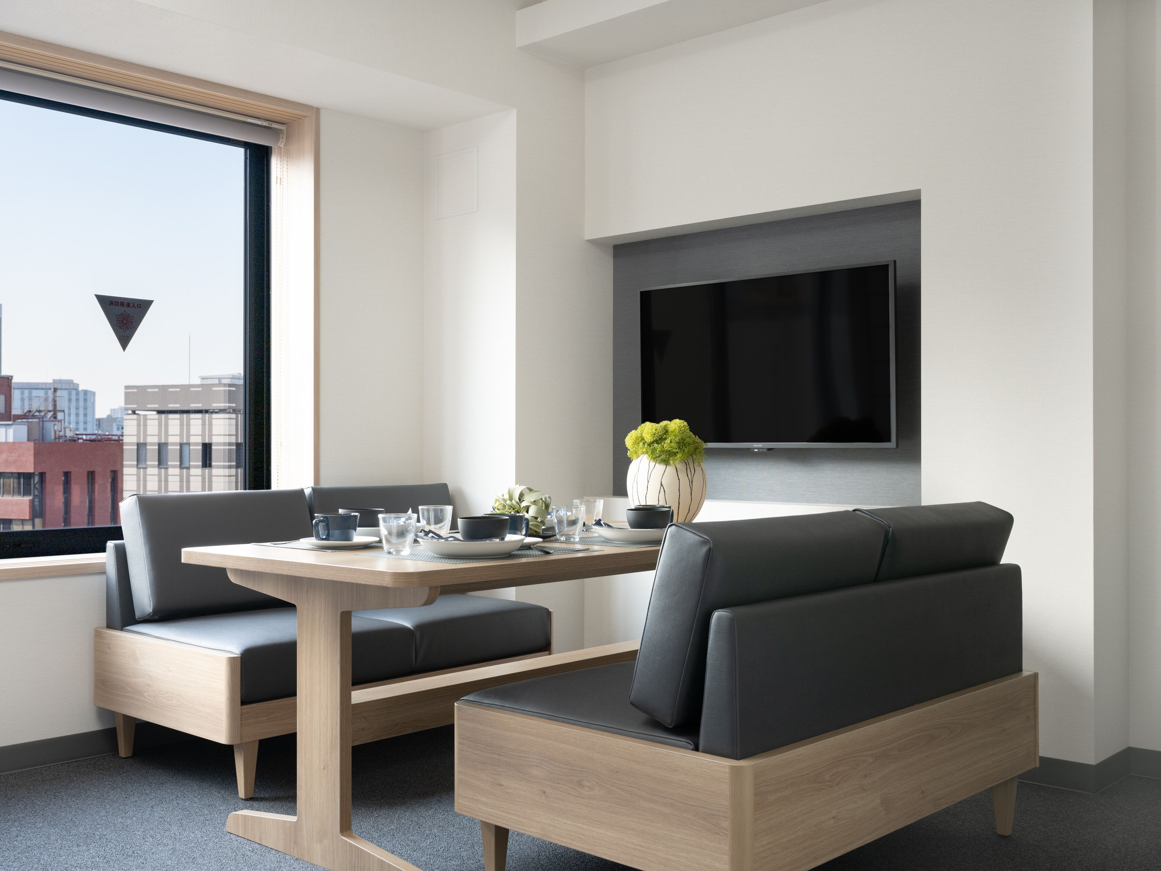 Um quarto moderno com sofá, mesa de jantar e televisão fixada na parede.