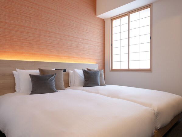Habitación de hotel con dos camas, una pared de ladrillo y un ventanal grande.