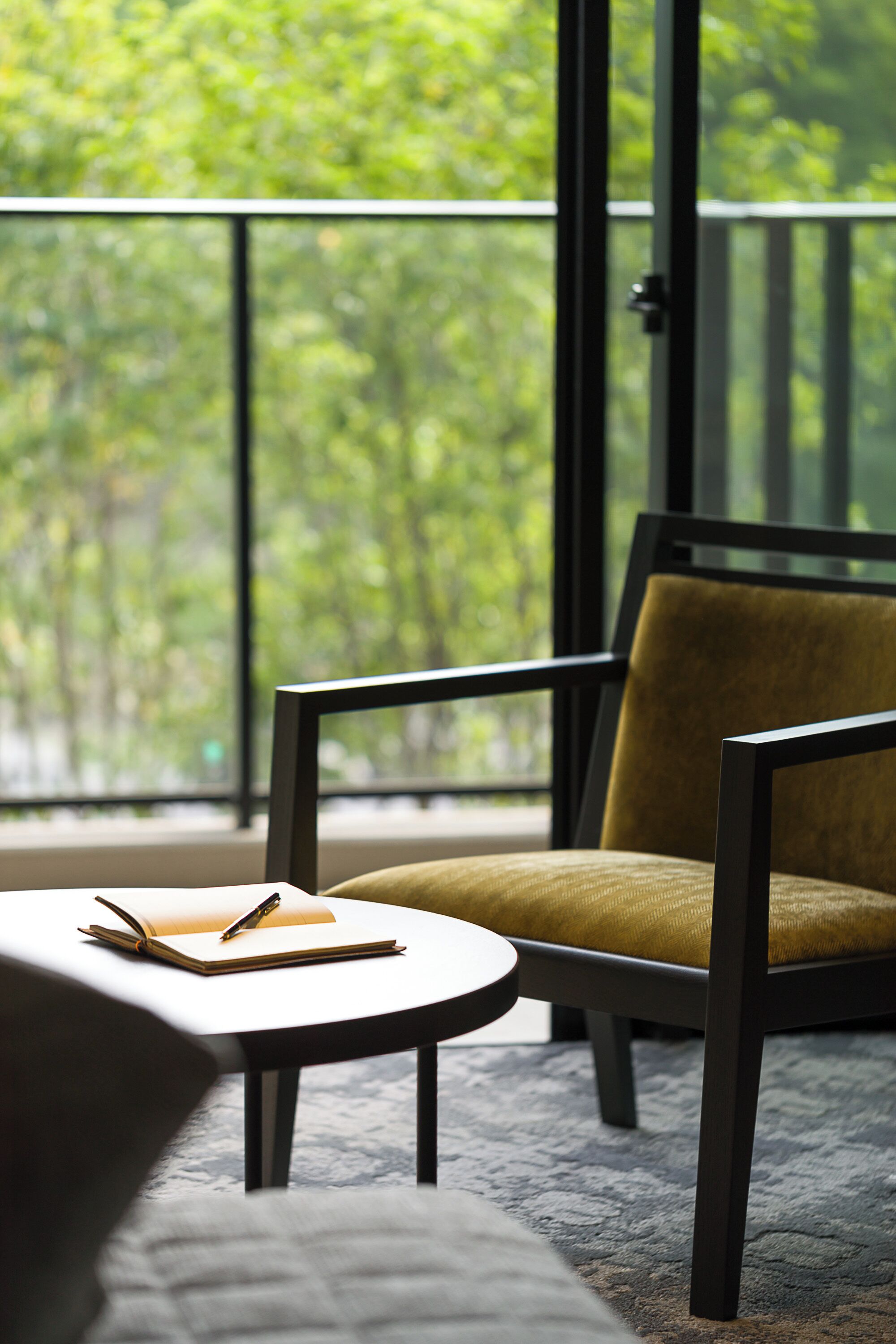 A modern room with a large window, a chair, a small table, and a sofa.