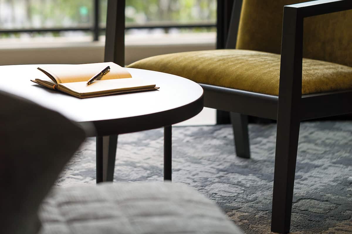 A modern room with a large window, a chair, a small table, and a sofa.