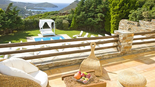A terrace with a pool, lounge chairs, and a wicker table with fruit. - Infinite Serenity: Villa Etheria – 4 Bed Luxury, Private pool, Gym (Andros)