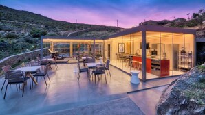 A modern glass house with a kitchen and dining area, surrounded by a natural landscape. - Infinite Serenity: Villa Etheria – 4 Bed Luxury, Private pool, Gym (Andros)