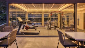 A modern gym with glass walls, exercise equipment, and a seating area. - Infinite Serenity: Villa Etheria – 4 Bed Luxury, Private pool, Gym (Andros)