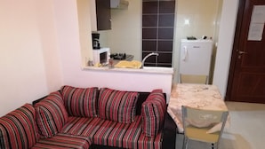 A compact living space with a striped sofa, a small dining table, and a kitchenette area. - Holiday rentals in Tunis (Tunis)